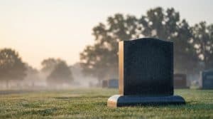 Polished granite upright headstone in a quiet cemetery at soft morning light, illustrating 2026 headstone cost ranges